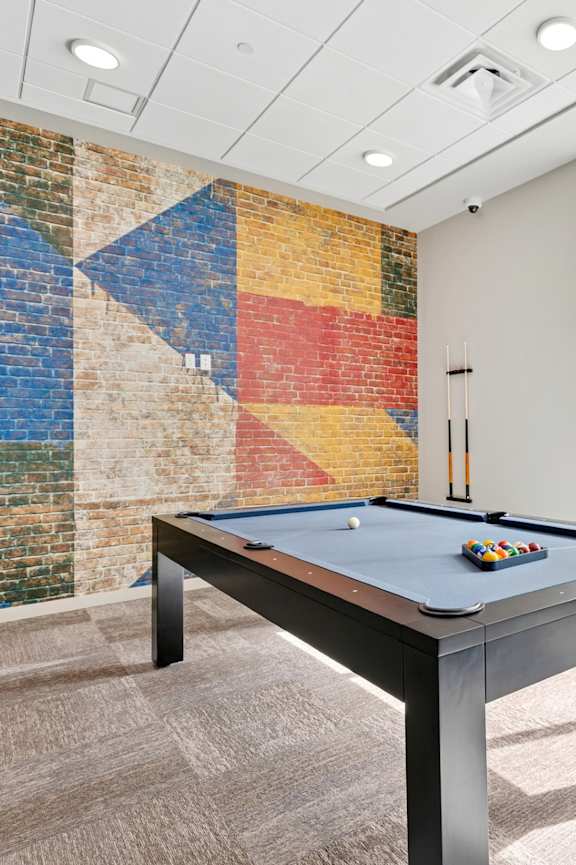 A pool table in a room with a brick wall.