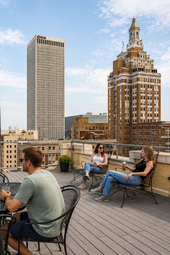 A group of people are sitting around a table on a rooftop patio.