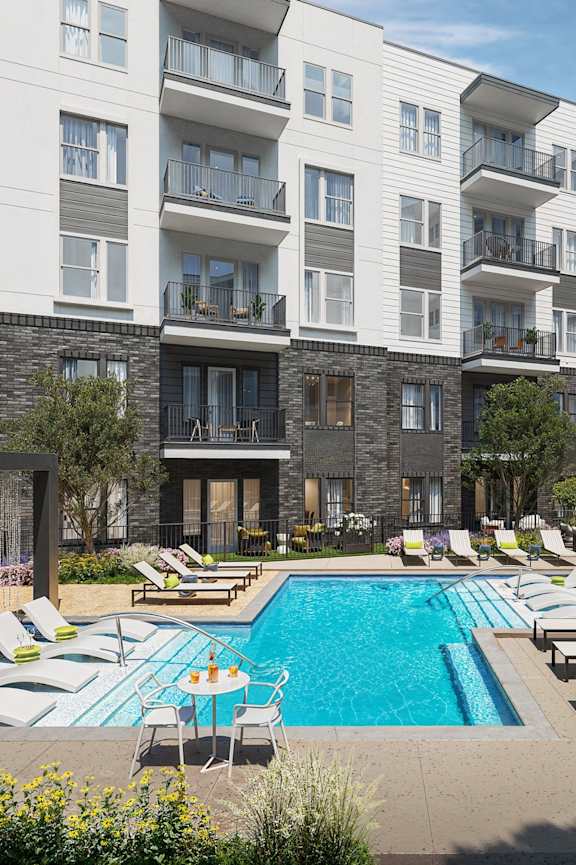 an outdoor swimming pool with lounge chairs in front of an apartment building
