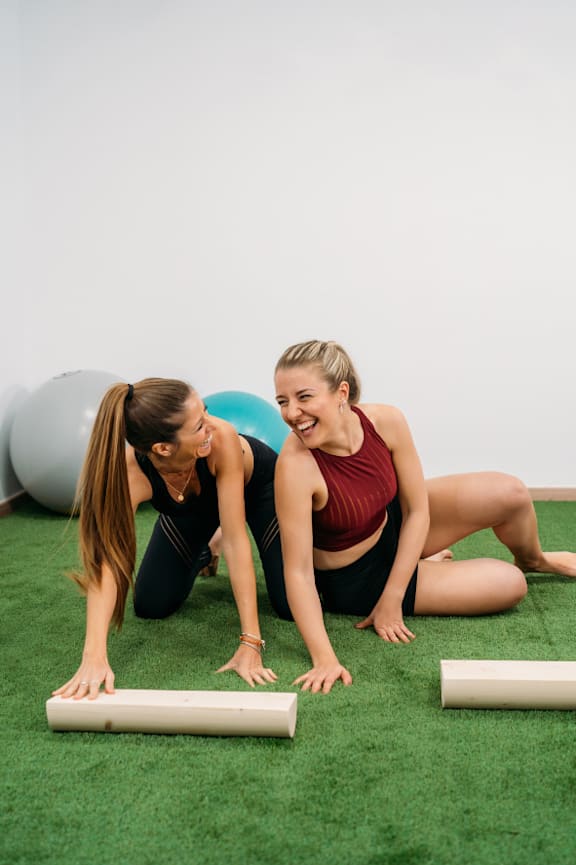 Two women doing push-ups in a gym.
