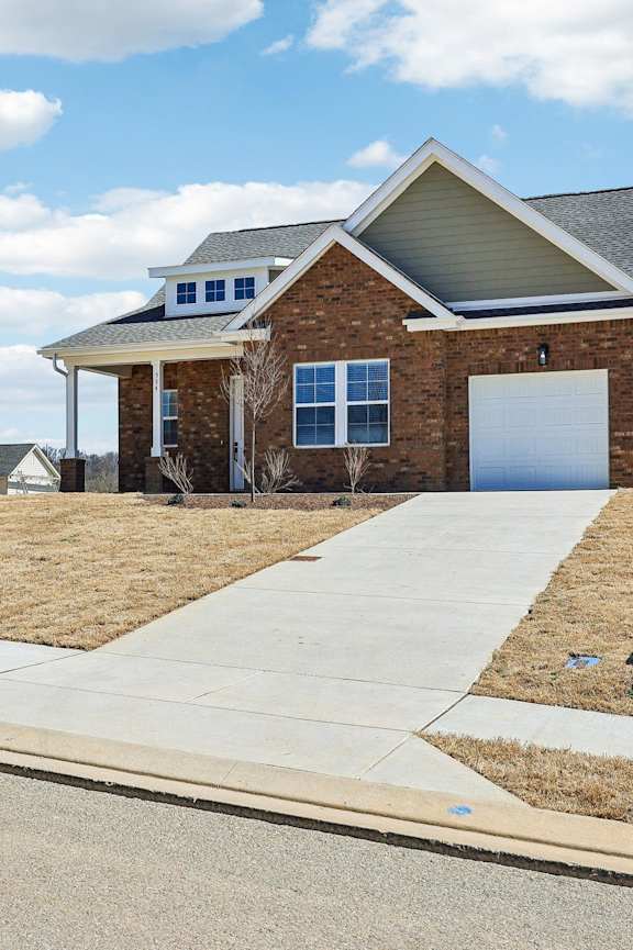 A brick house with a white garage door and a grey roof.