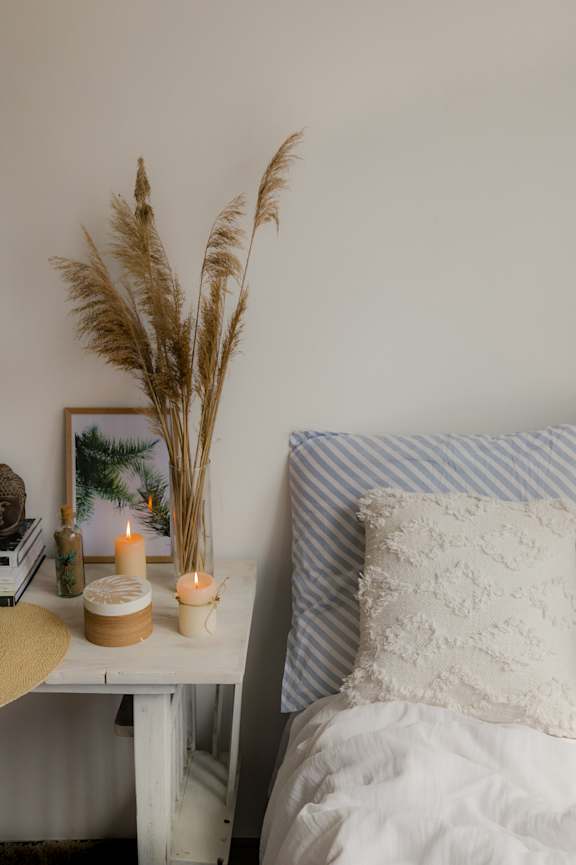 A white bed with a blue striped pillow and a white pillow with lace on it.