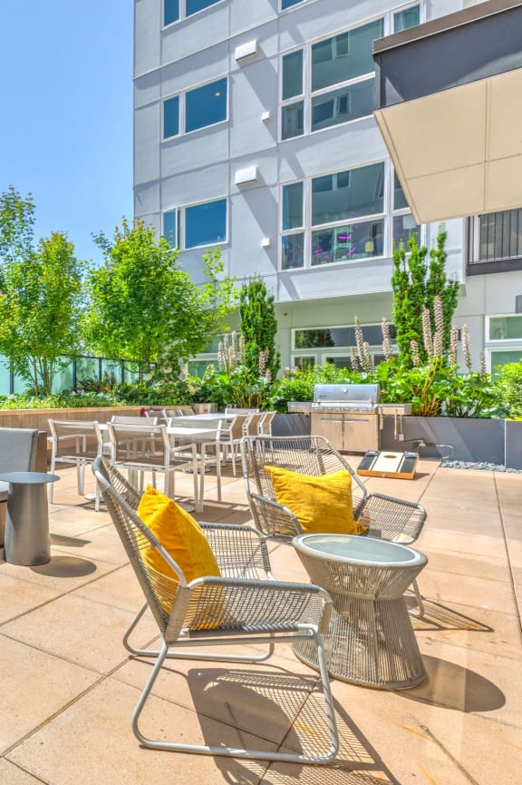 a patio with couches tables and chairs and a building in the background
