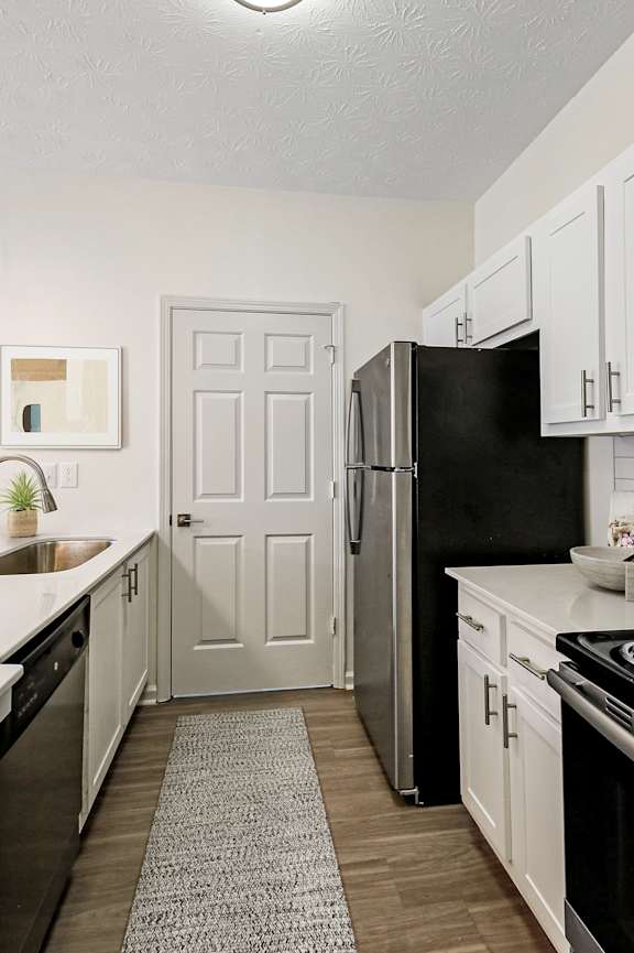 A kitchen with black appliances and white cabinets.