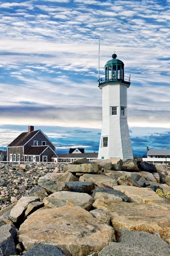 a lighthouse on the shore of a rocky beach