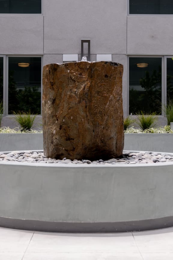 a large rock sits in a fountain in front of a building