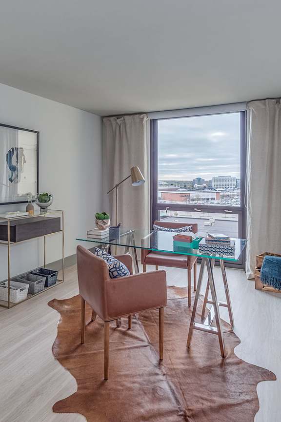 A room with a brown leather chair and a glass table with a plant on it.