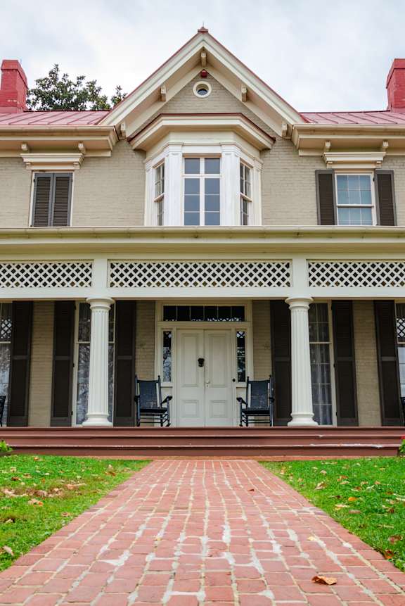 A large house with a red roof and a brick walkway in front.