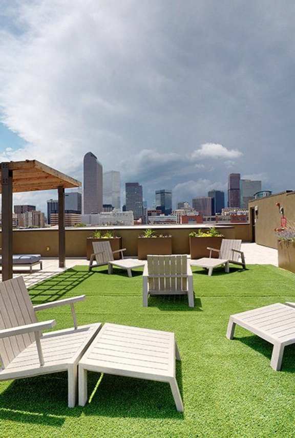 A rooftop patio with white furniture and a view of the city skyline.