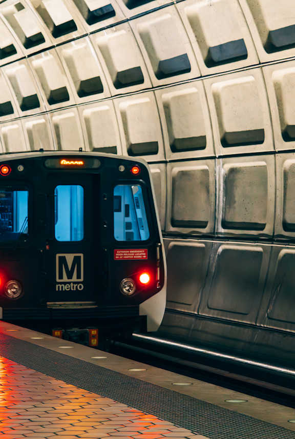 A black train with the Metro logo on the back is on a subway platform.