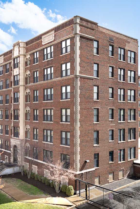 A large red brick building with a parking lot in front.