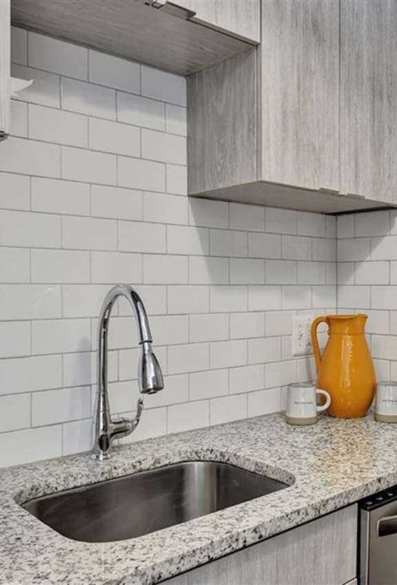 A kitchen with a sink and a yellow pitcher.