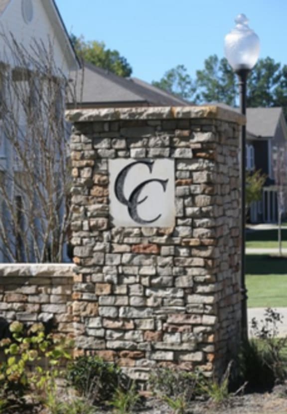 a stone wall with a cc on it in front of a house