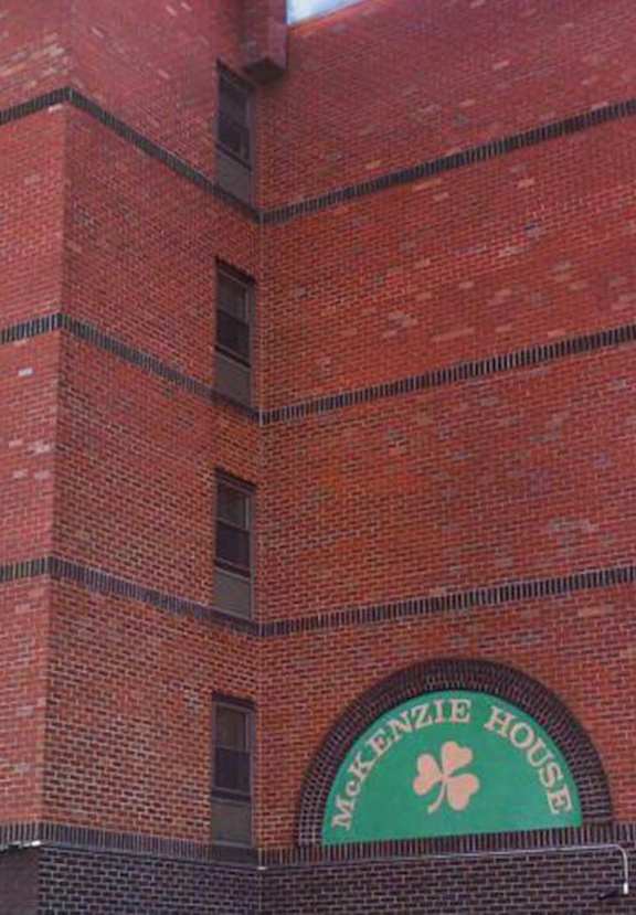 a photo of a tall red brick building with a green sign on it