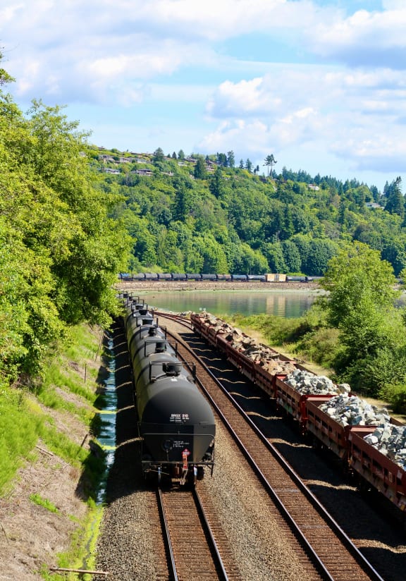 a train is traveling down the tracks next to a body of water
