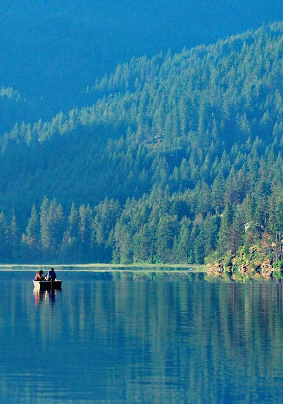 Two people are fishing in a calm lake.