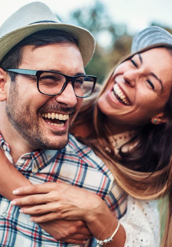 a man and woman wearing hats laughing and holding each other