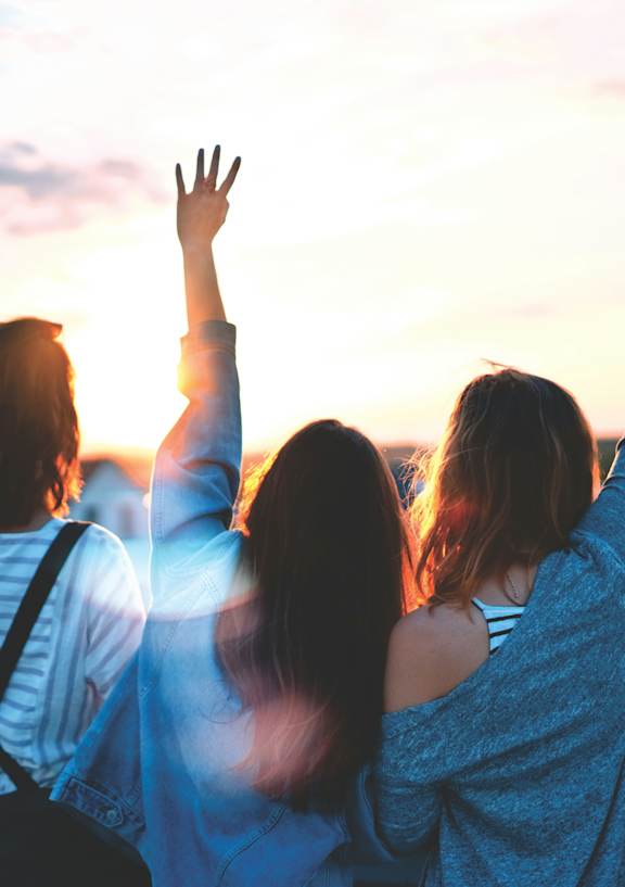 Three people are standing on a bridge with their arms raised in the air.