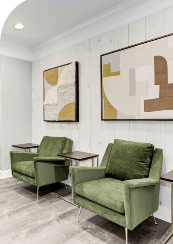a living room with green chairs and a painting on the wall