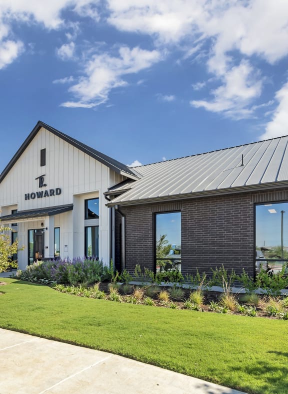 the front of a building with a lawn and a sidewalk