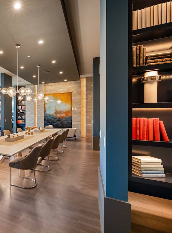 a dining room with a long table and chairs and a library