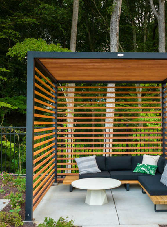 A modern outdoor seating area with a wooden slatted wall and a white table.