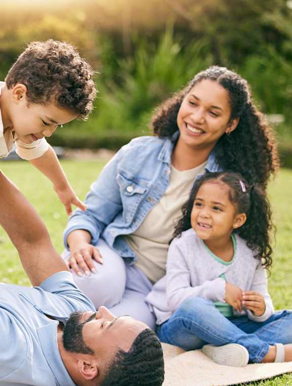 A family of four is enjoying a day outside on a blanket at Poplar Place Apartments, Illinois 62703