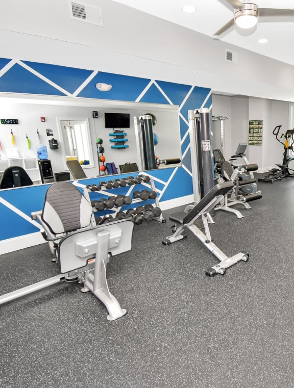 a spacious fitness room with cardio equipment and weights