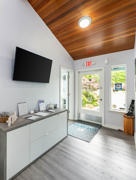 A room with a wooden ceiling and a white wall with a black TV mounted on it.