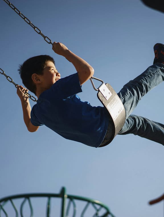 A boy is swinging on a swing set.