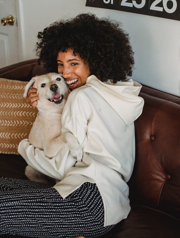 a woman sitting on a couch holding a dog