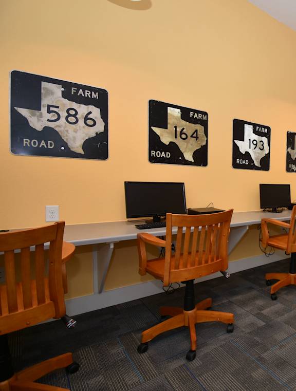 A conference room with a white table and chairs and a wall with signs that say Farm Road 586, Farm Road 164, and Farm Road 193.
