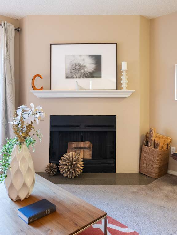 A living room with a fireplace, a vase with flowers, a book, and a framed picture on the wall.