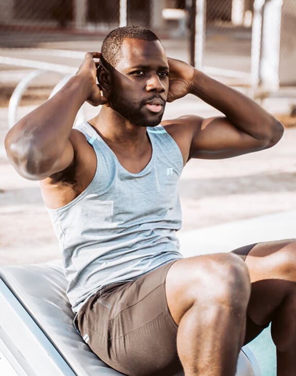 a man sitting on a car with his hands behind his head