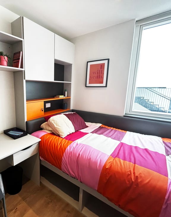 a bedroom with a bed and a desk and a window