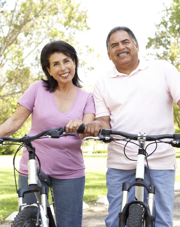 a man and a woman walking their bikes in a park