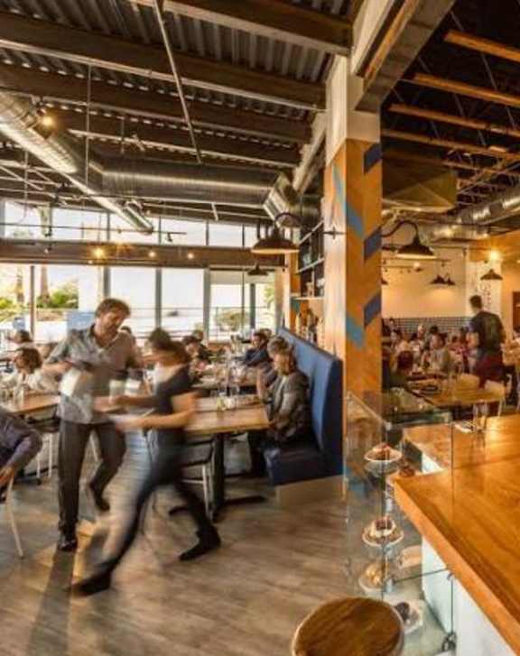 A busy restaurant with people dining and a bartender behind the bar.