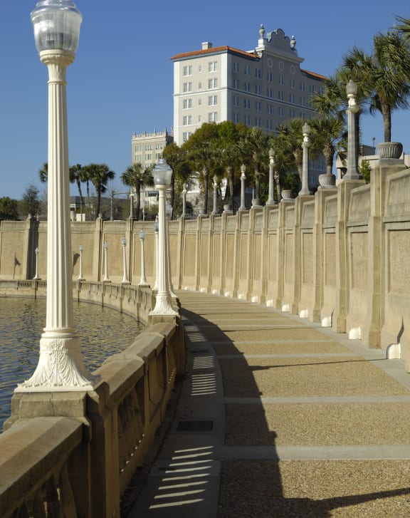 a walkway next to a body of water with a large building in the background at Audubon Oaks, FL 33809