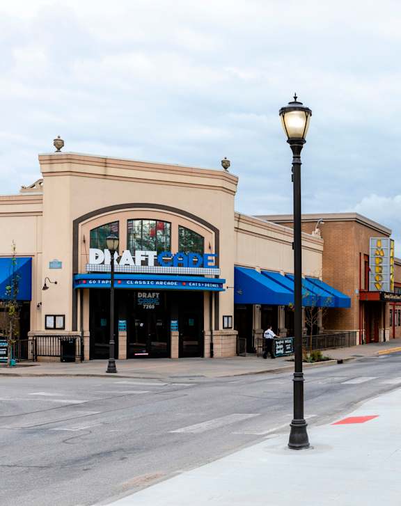 A street view of a shopping area with a blue awning and a sign that says "Draft".