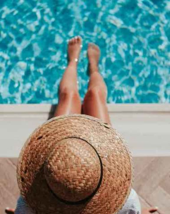 a person with a straw hat laying on the side of a pool