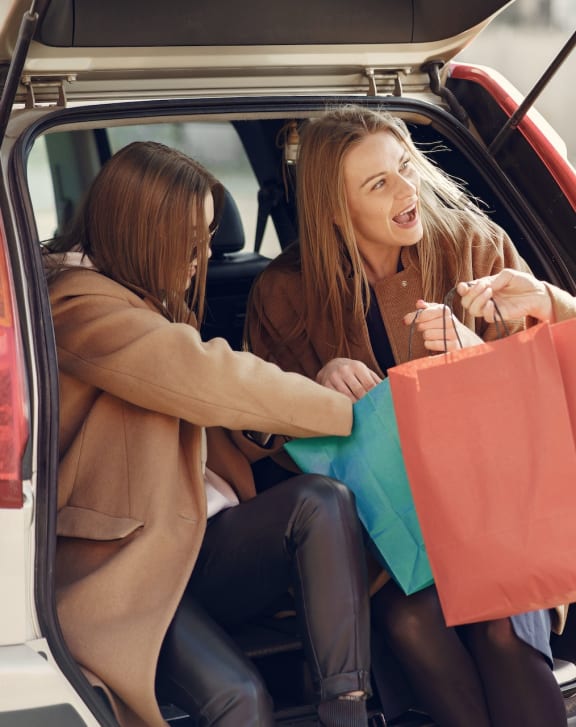 three women getting out of a car with shopping bags