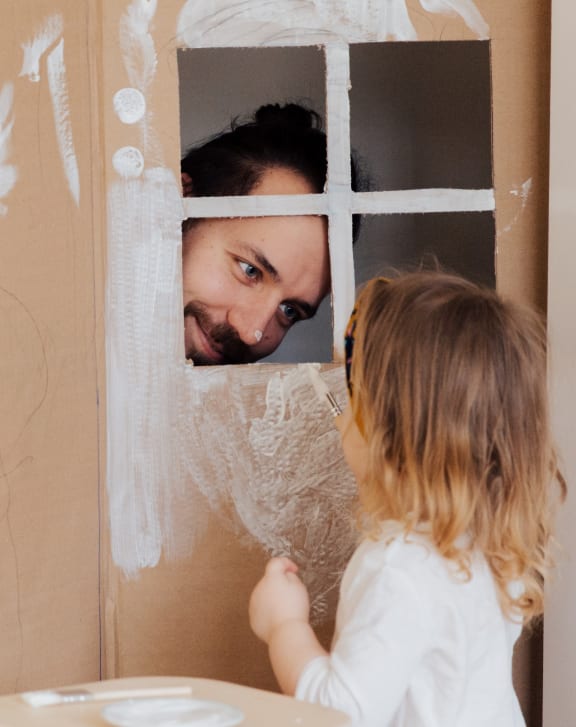 a little girl looking in a mirror at a man in a beard