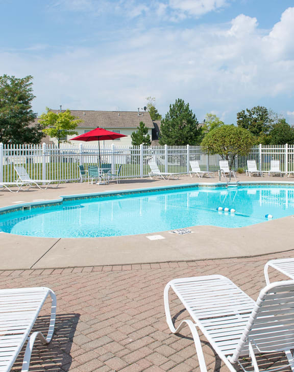 our resort style swimming pool is surrounded by chairs and a white fence