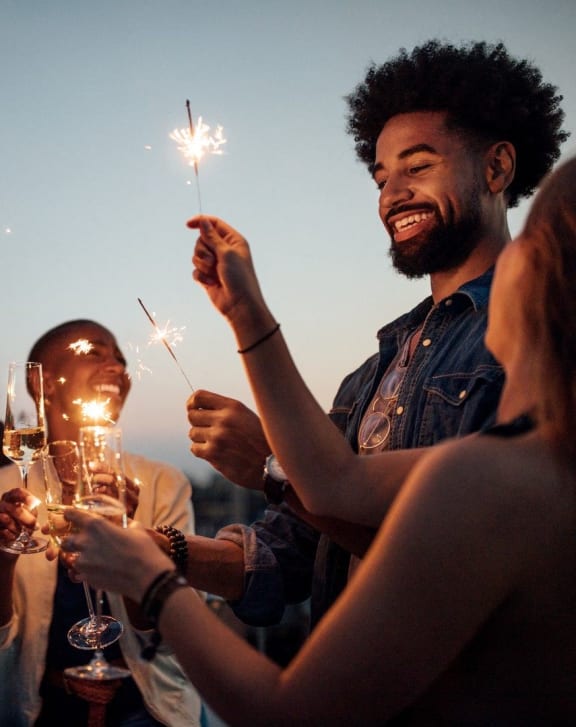 people celebrating with sparklers at a party with wine glasses