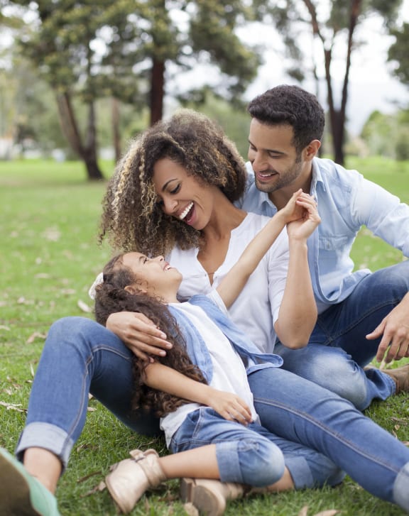 a man and woman sitting on the grass with a child