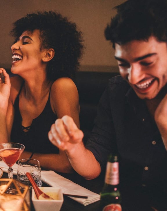 a group of people sitting at a table laughing and eating at a restaurant
