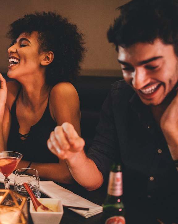 A group of people laughing and enjoying a meal together.