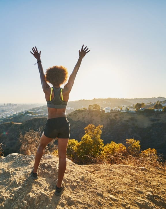a woman standing on a rock with her hands in the air