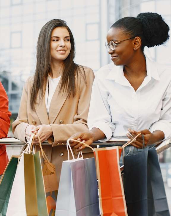 Three women with shopping bags in the city.
