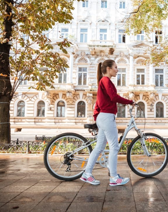 a woman walking her bike in front of a building